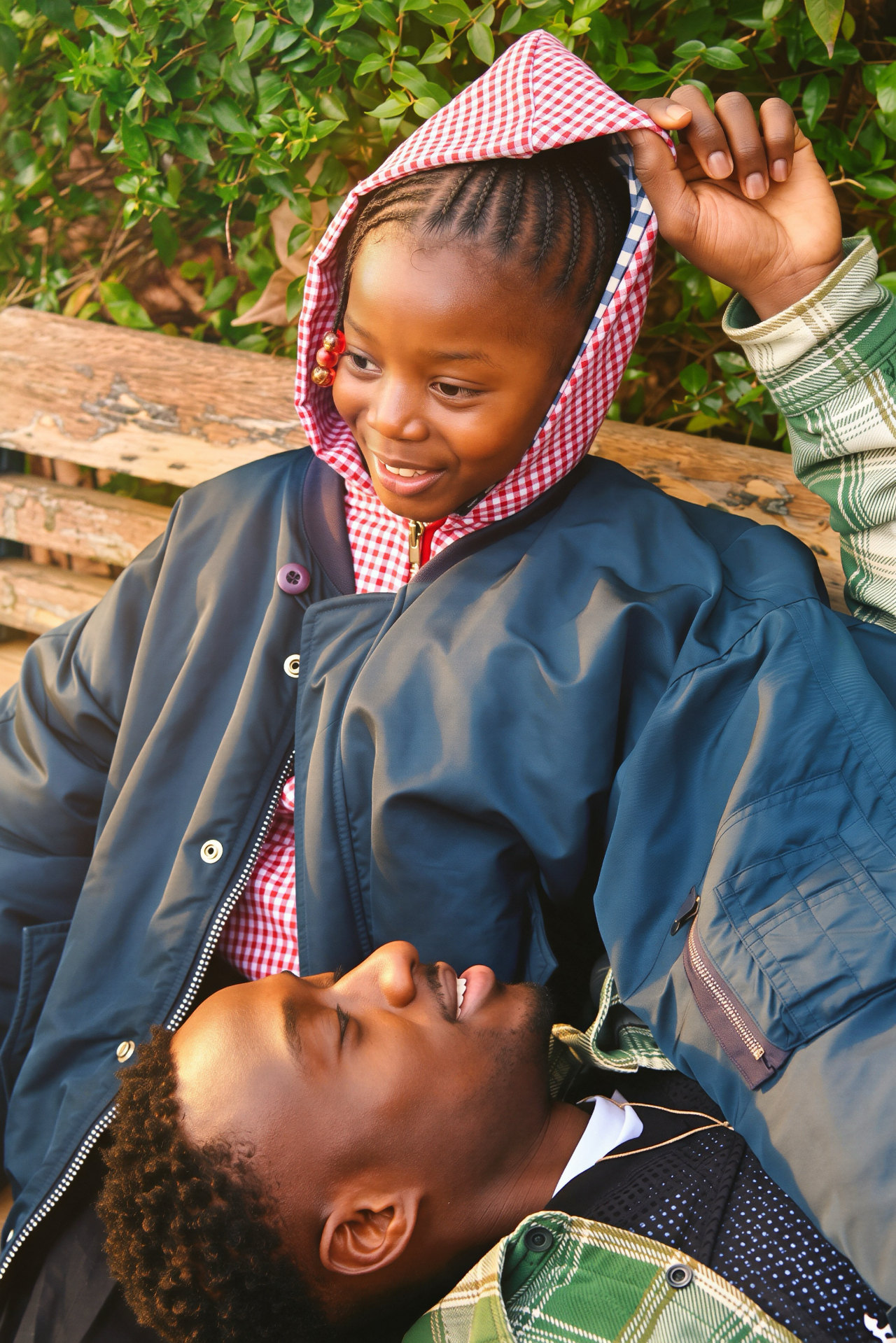 A father and daughter laughing together on a park bench