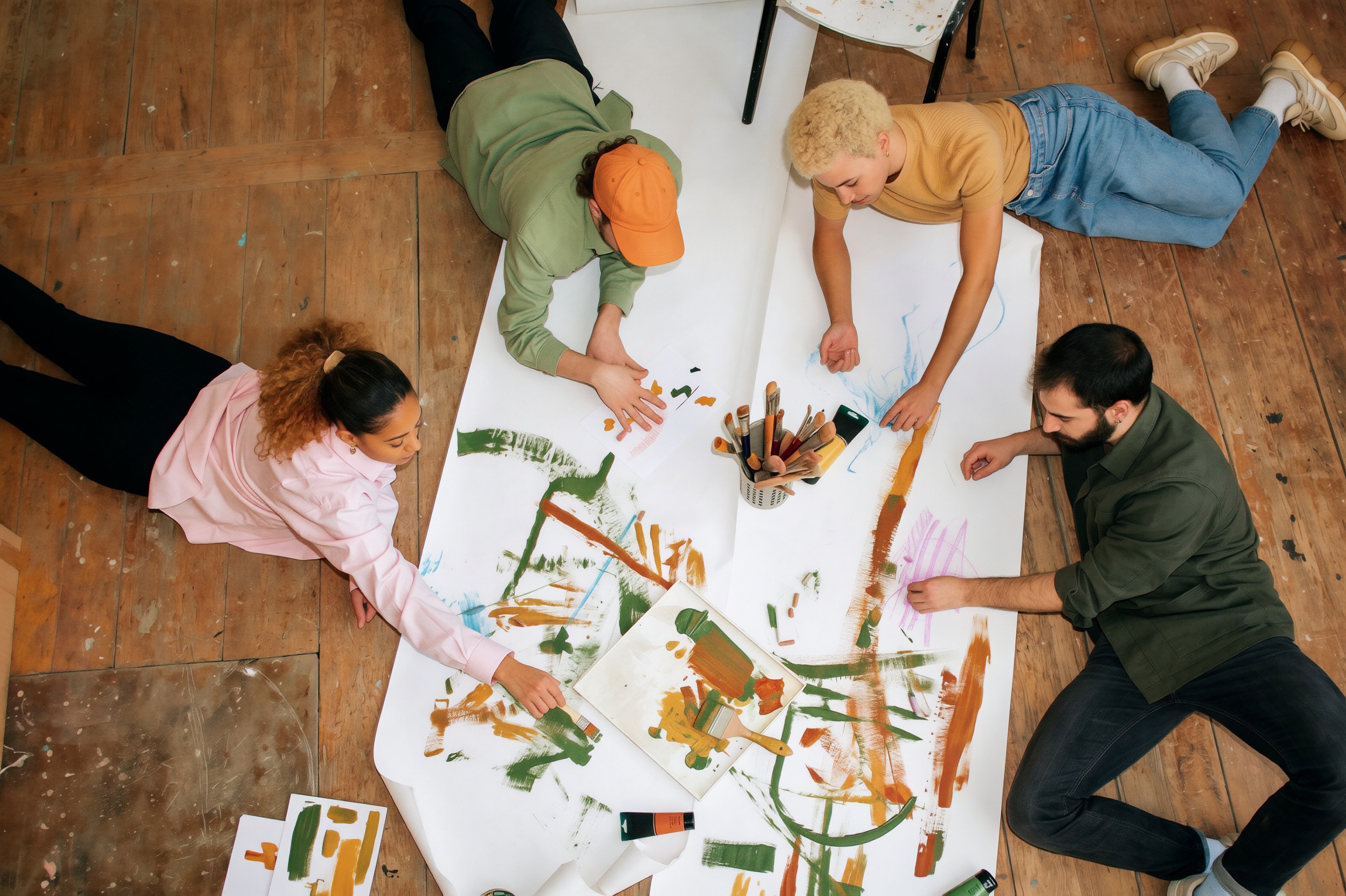 Four friends painting one long sheet together, seen from above