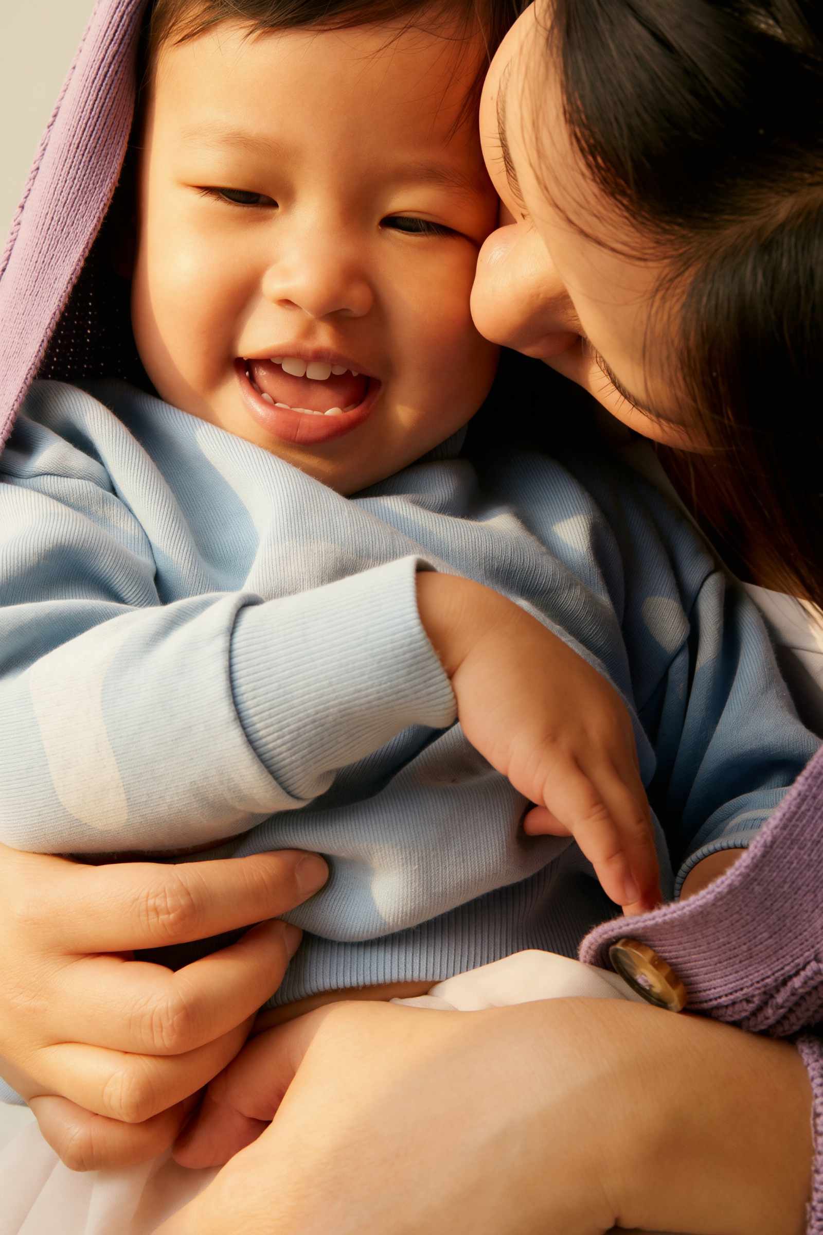 A mother holding her laughing toddler close
