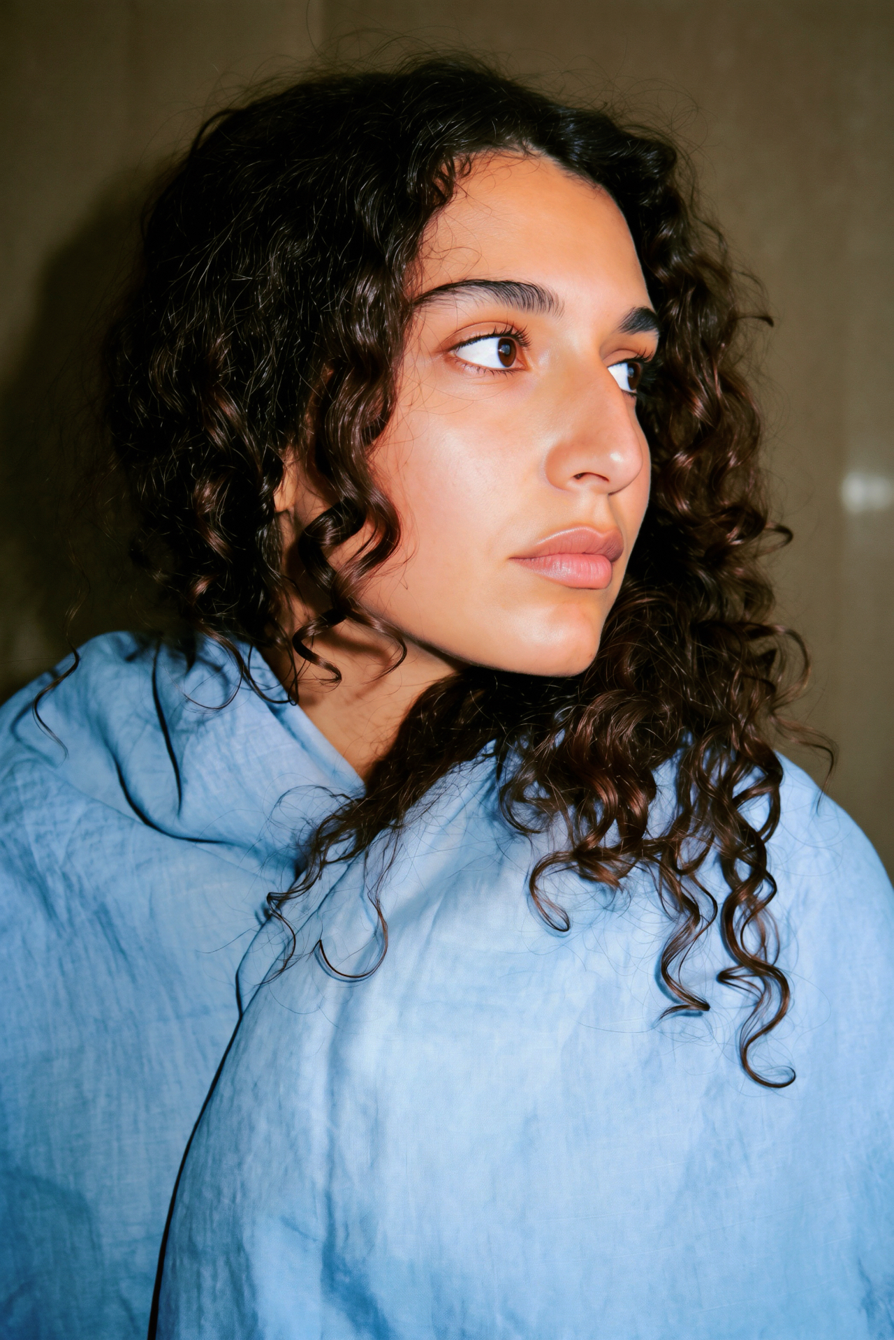A woman in blue linen looking to the side in evening light