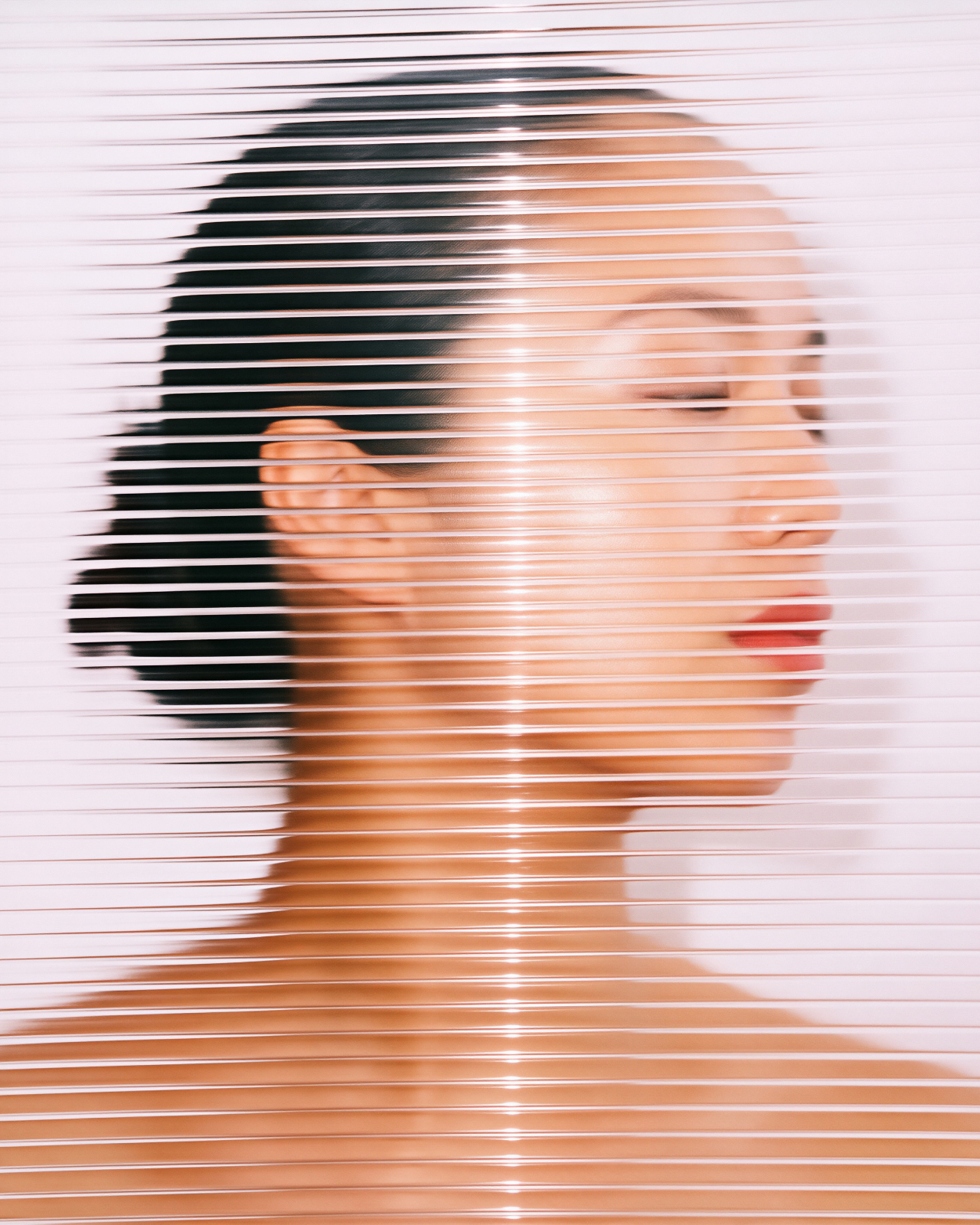 A woman in profile, eyes closed, seen through slatted glass